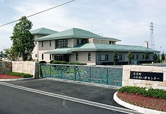 施設名の彫り込まれたプレートのある門の奥に見える、緑色の屋根と白い壁の北方町ふれあい水センターの写真