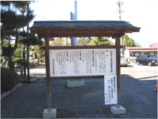屋外に建つ細かな文字が縦書きに書かれた説明板の写真