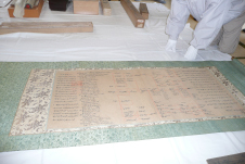 細かい文字がたくさん書かれている緑色の掛け軸を横から撮影した写真