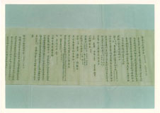 白い布の上に文字の書かれた開いた状態の巻物の一部分を上から撮影した写真