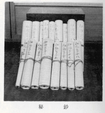 箱の様な物の前に紐で閉じた状態の巻物が2列に立てかけてありそれを前から撮影した白黒写真の下に「秘鈔」と書かれた写真
