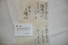 白い布の上に文字の書かれた色褪せたA4ほどの紙とその上に「秘鈔」と文字と説明文の様な物が書かれた小さい紙が置かれている写真