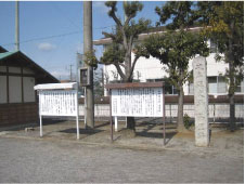 文字の書かれた縦長の石碑とその横に文字の書かれた茶色と白色の2つの説明板が設置されている様子の写真