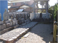 砂利の地面に3段に積み重ねられた石の句碑が横一列に並べられその奥に井戸がある様子の写真