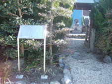 左手に説明の看板がありその脇に木々に囲まれた細い砂利道がありその奥に附句碑が見える写真