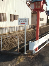 水路脇の赤い灯篭の街灯の近くに設置された北方城跡へ赤い矢印で示している看板の写真