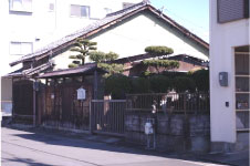 住宅街に囲まれた土地に瓦屋根の平屋の家と小さな瓦屋根のついた門が特徴的な五竹坊居宅跡の写真