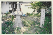 木漏れ日が差し込む建物に囲まれた一角に石を重ねて作った古墳の写真