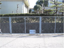 堀を仕切っているフェンスの中央に郡界石旧位置跡と書かれた看板が設置されている写真