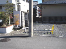 近くに電信柱が立ち住宅街の一角に砂利で敷き詰められた高札場跡の写真