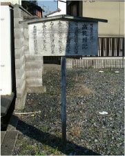 砂利の敷き詰められた土地に木製の案内板が立っている写真