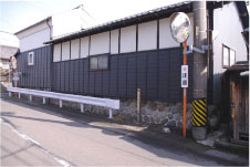 緩やかな坂の途中に黒い壁の家屋が2軒並んで立っている柱本高札場跡の写真