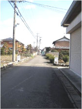 右側に背の高い倉庫があり奥にも住宅が立ち並んでいる芝原1~2丁目付近の写真