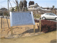 右側にシルバーの車が駐車している小道の脇に東山道の白い案内板と標柱が設置されている写真