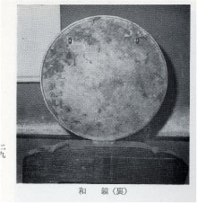 台座に固定された真ん中が白くなっている様子の和鏡の裏側の昔の白黒の写真