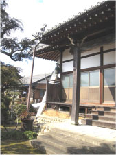寺の外壁から飛び出た梁に吊るされた半鐘を遠くから寺ごと写した写真