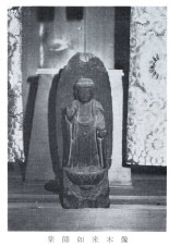 右手を前に出した木像を撮影した白黒の写真