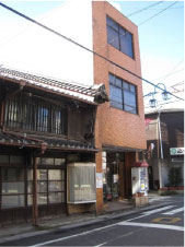 卯建のある日本家屋と茶色の外壁のビルの写真
