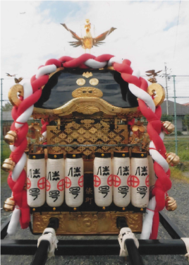紅白のしめ縄と白いちょうちんが並んで設置されている神輿を正面から撮影した写真