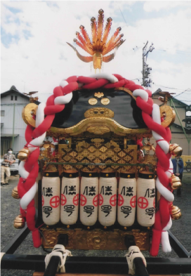 紅白のしめ縄と白いちょうちんが並んで設置されている神輿を背面から撮影した写真