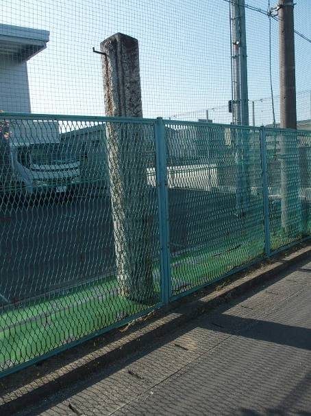 学校の敷地と道路との境のフェンスのすぐ横に建てられている石造りの門柱の写真
