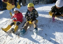 小さなソリに乗って雪遊びをしている園児たちの写真