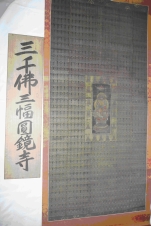 「三千佛三幅圓教寺」と書かれた張り紙の右横に、仏様が一体真ん中に描かれた巻物が展示されている様子の写真