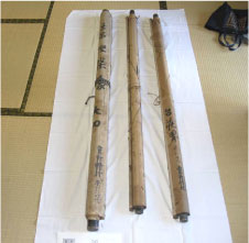 畳の上に白い布を敷きそこに涅槃像図を含む三本の絵巻物を巻物が閉じた状態でおいている写真