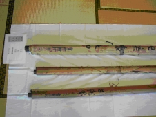 畳の上に白い布を敷いて三本の絵巻物を並べている写真