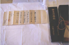 白い布の上に年季の入った紙に黒地で文字が書かれた秀吉朱印状と黒い箱の写真