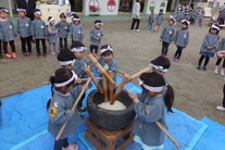 児童たちが臼と杵で餅つきをしている写真