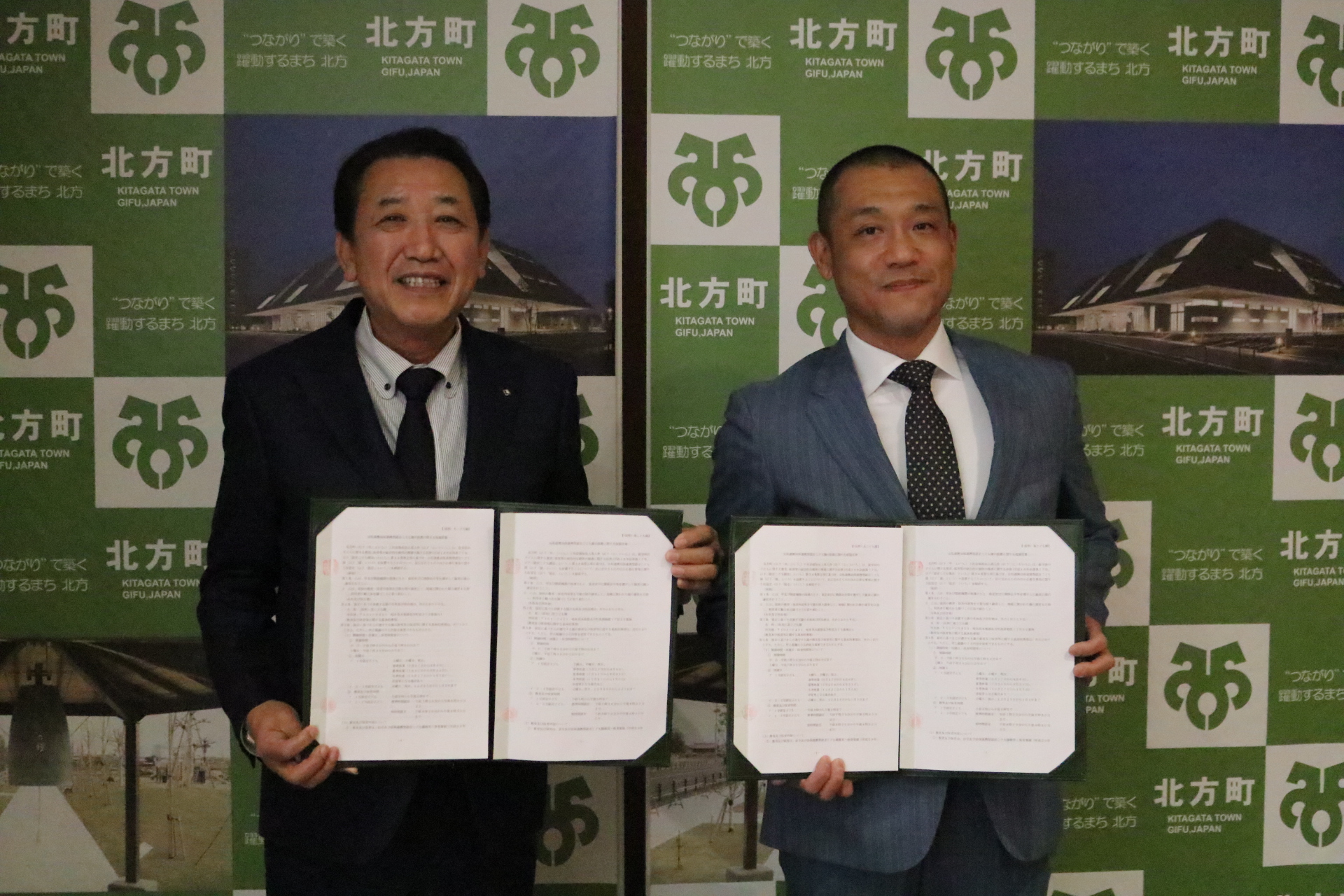 戸部町長（左）と川口業務執行理事（右）が仮契約の証書を手に記念撮影している写真